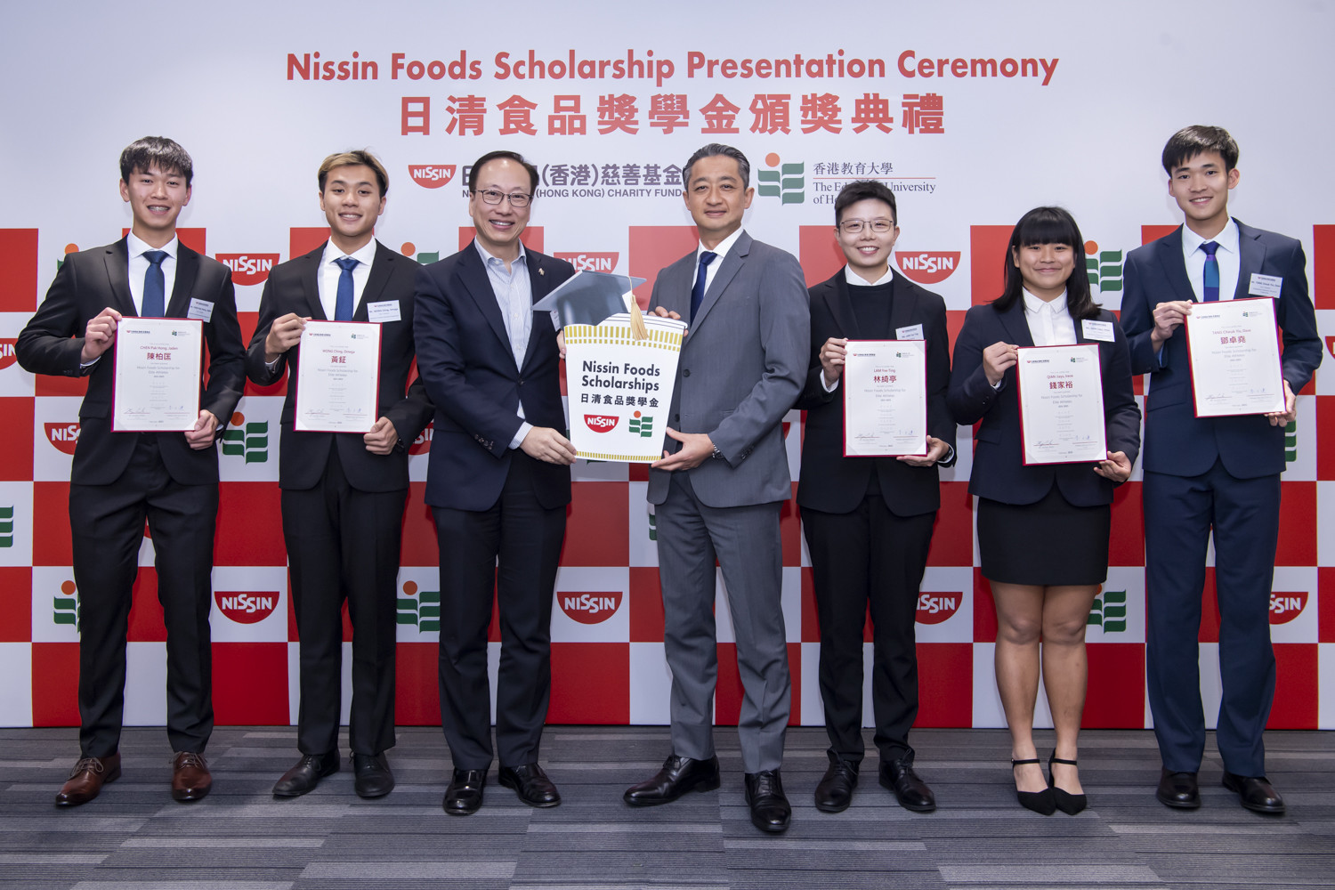 日清食品（香港）慈善基金主席安藤清隆先生（中间右）及香港教育大学副校长（研究与发展）陈智轩教授（中间左）于2025年2月18日出席2024/2025学年日清食品精英运动员奖学金颁奖典礼。五名奖学金得主参与典礼，包括四名新得奖的精英运动员学生陈柏匡先生（左一）、黄钲先生（左二）、林绮亭小姐（右三）及钱家裕小姐（右二），以及于本学年获得续期奖学金的精英运动员学生邓卓尧先生（右一）
